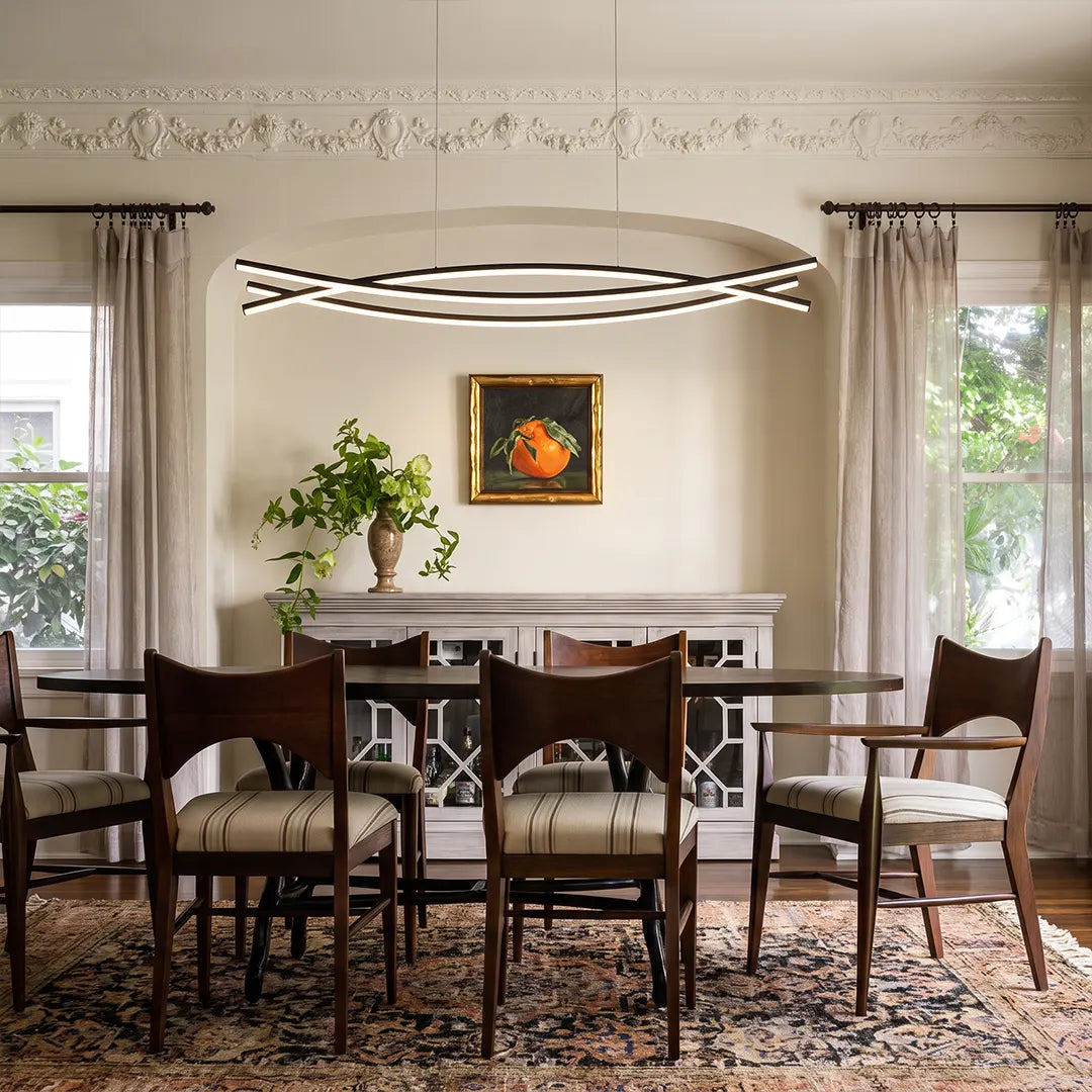 Wave hanging light suspended above a dining table in a classic room with curtains and framed artwork.