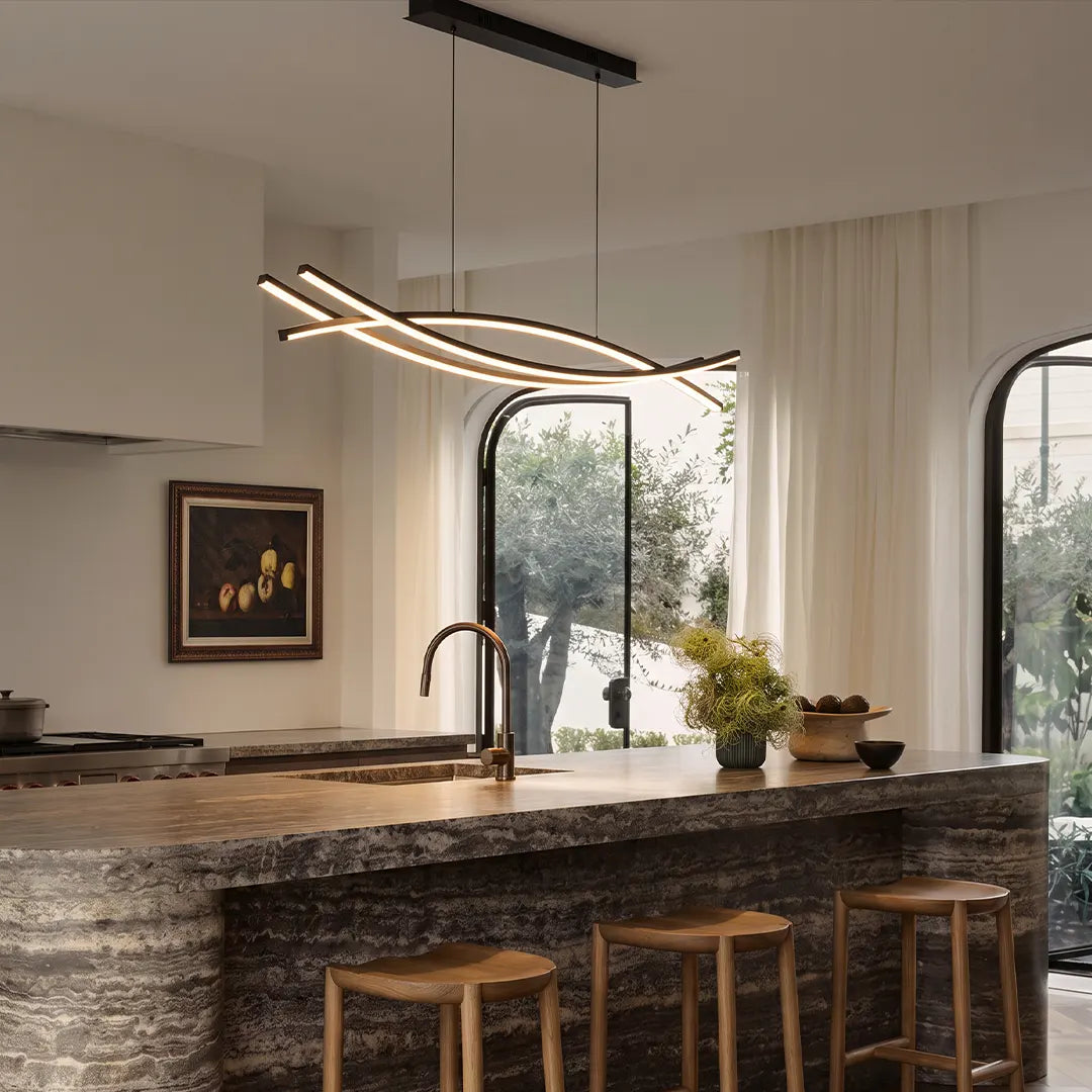 Wave hanging light above a kitchen island in a bright modern space with stone counters and arched windows.