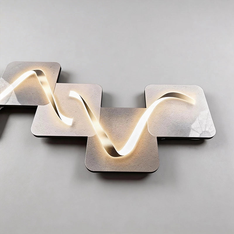 Wave pattern wall sconce displayed horizontally, featuring a flowing illuminated ribbon design across layered square backplates.