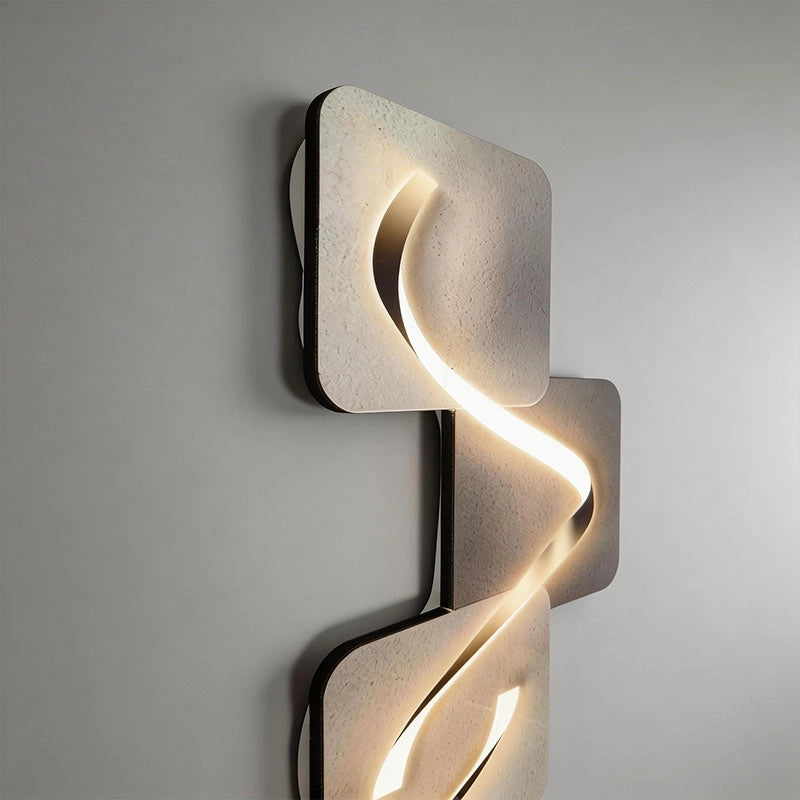 Wave pattern wall sconce mounted vertically on a wall, combining overlapping geometric panels with a sculptural illuminated wave.