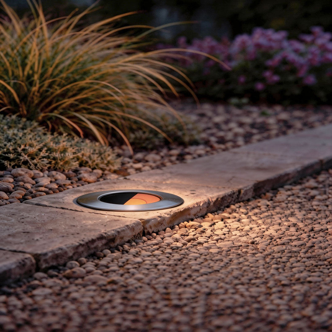 Well lights in concrete with a sleek design, illuminating a garden pathway at night.