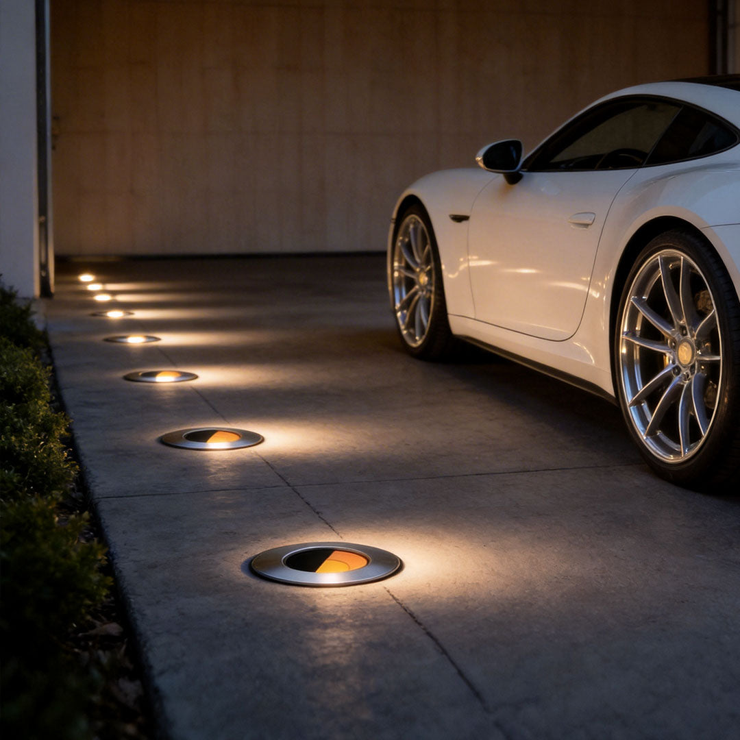Well lights in concrete with a warm glow, lighting up a driveway beside a car.