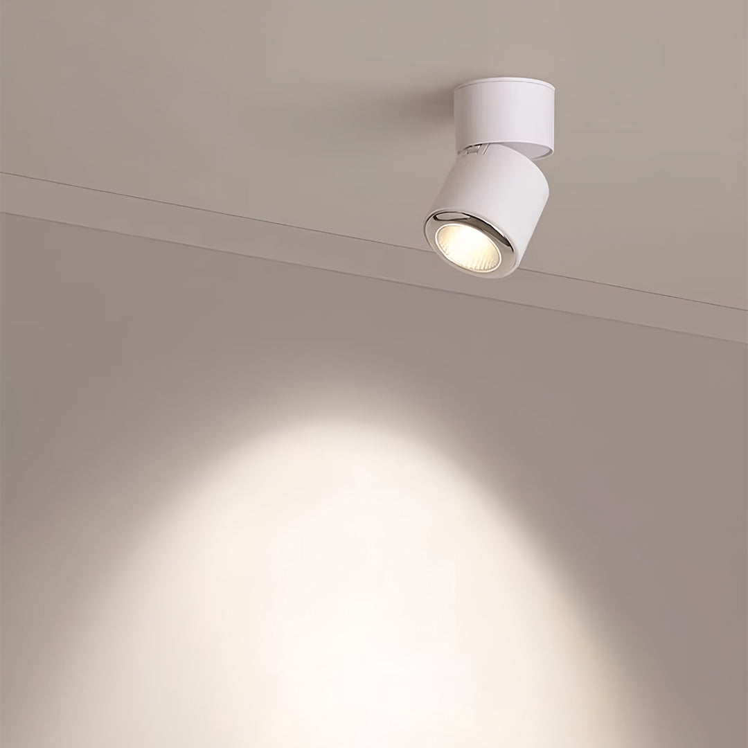 White adjustable spotlight creating dramatic downlight on neutral ceiling surface