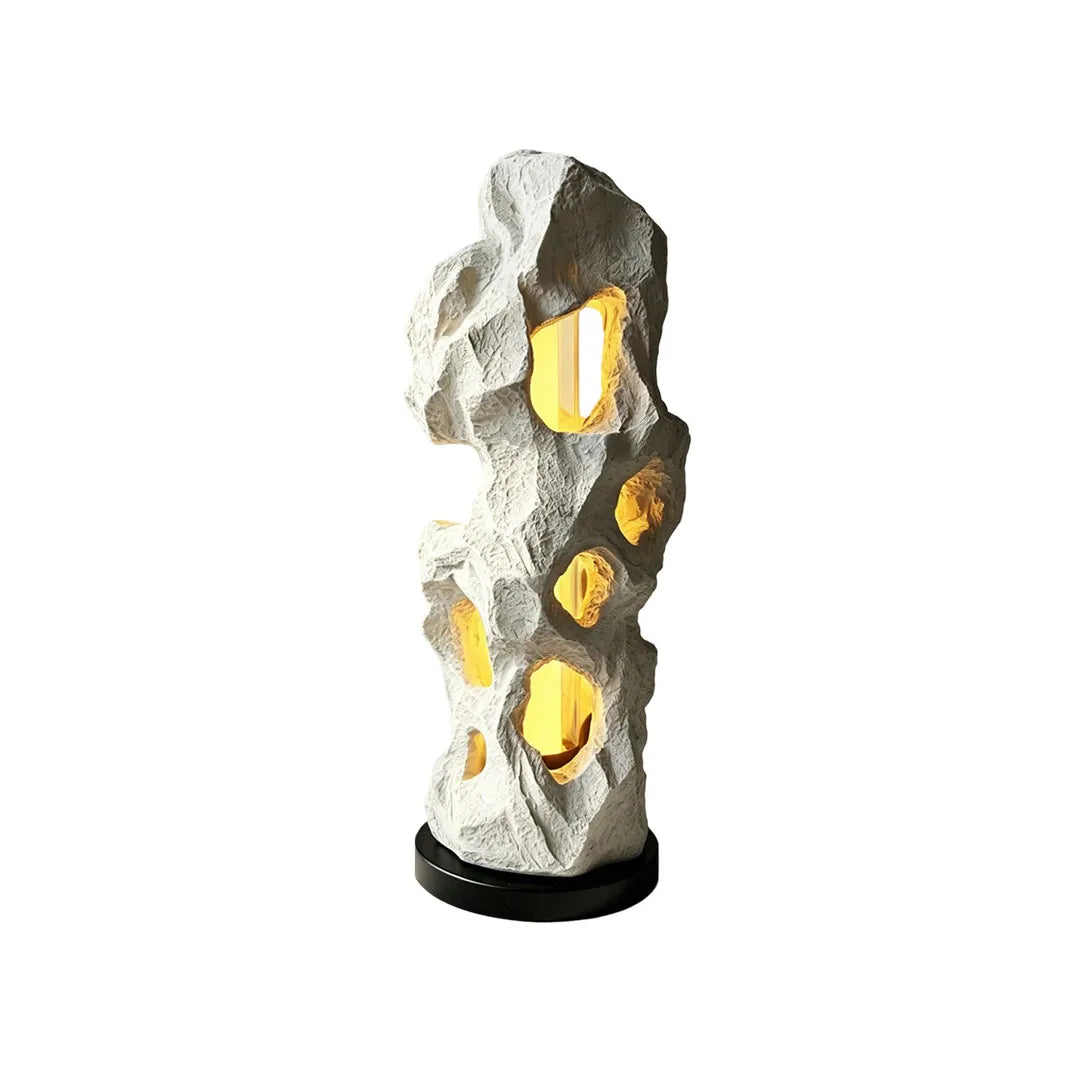 White artistic table lamp with an organic rock-inspired sculptural design and warm internal lighting.