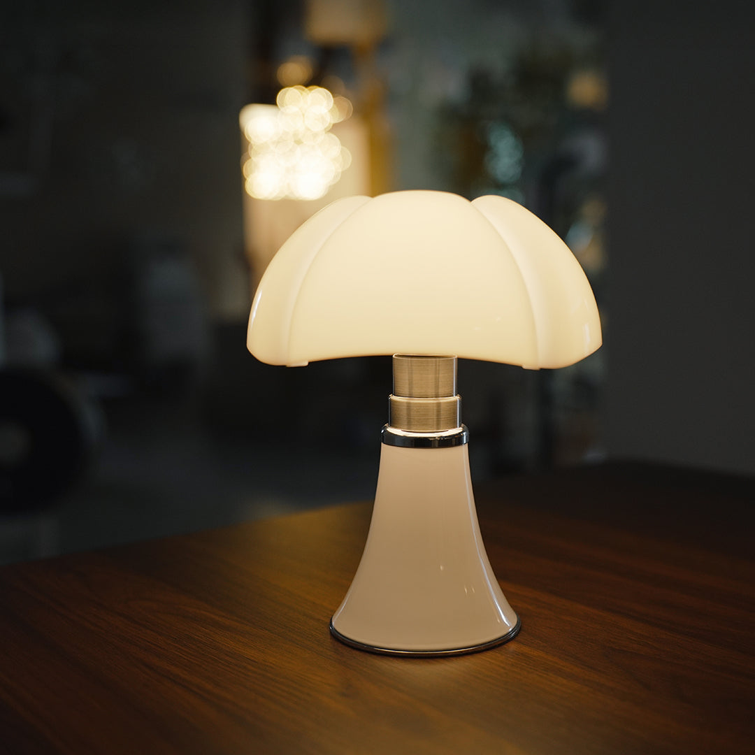 White Bauhaus lamp with glossy shade, creating soft warm light on wooden table.