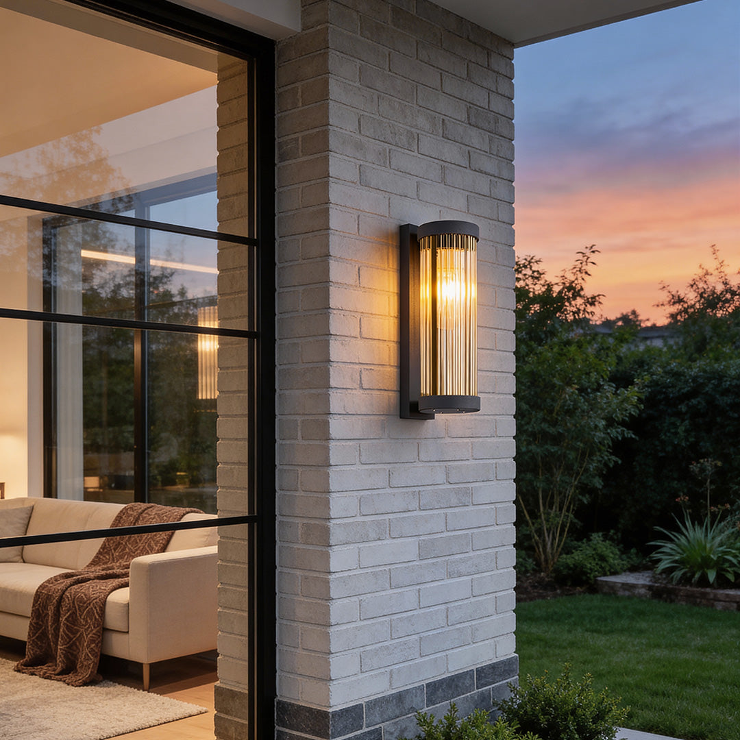 White brick exterior patio wall featuring contemporary outdoor wall mount lights installed next to large glass windows at sunset.