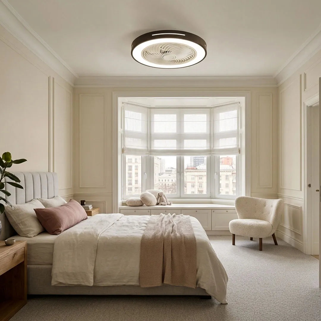 White ceiling fan flush mount with light mounted in a cozy bedroom with a large bay window and soft furnishings.