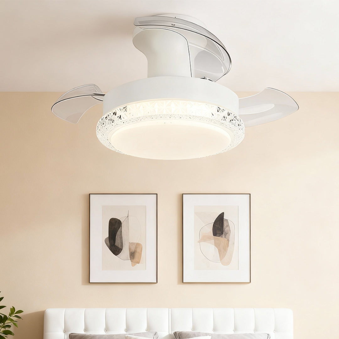 White ceiling fan with light showing retractable blade design in bright room with framed artwork and white sofa.