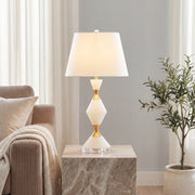 Elegant white contemporary table lamps with gold diamond stone stem on a marble plinth beside sofa.