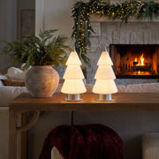 White contemporary table lamp styled on a console table in a cozy holiday living room with a fireplace and festive greenery.