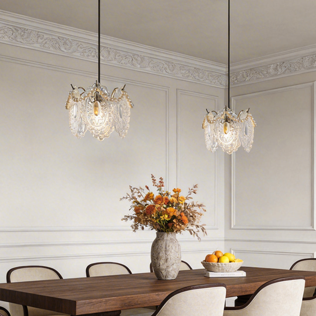 Modern white glass pendant lights illuminating a dining table with a floral centerpiece.