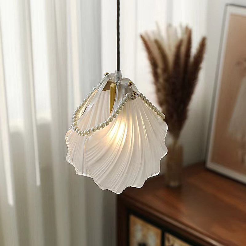 White glass pendant lights with a pearl embellishment, casting a soft glow in a room.
