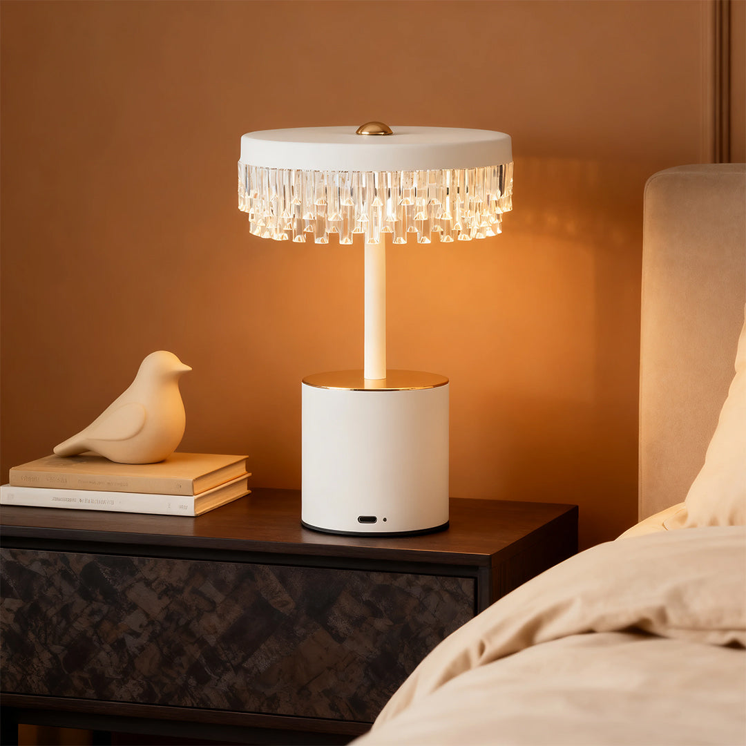 White and gold fringe table lamp with clear crystal fringe shade providing warm bedside ambient lighting.