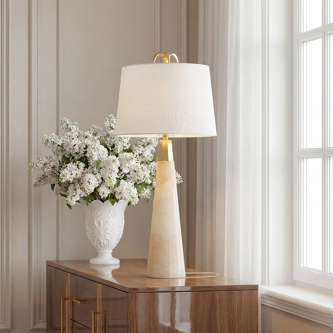 Luxury white marble table lamp with a tapered faceted base and gold accents on a wood sideboard