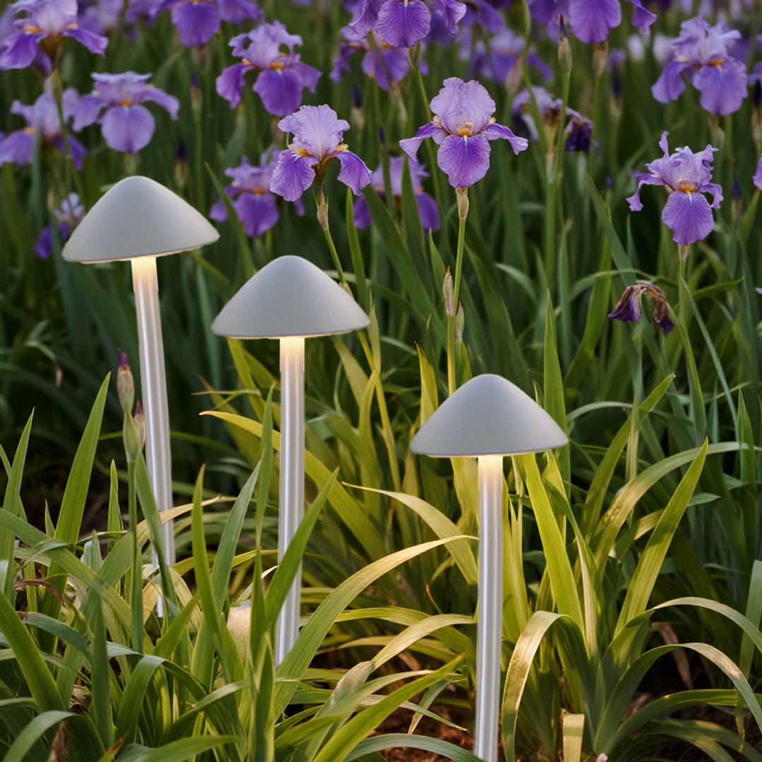 White mushroom garden lights clustered in purple flowering garden bed creating charming decorative outdoor lighting display
