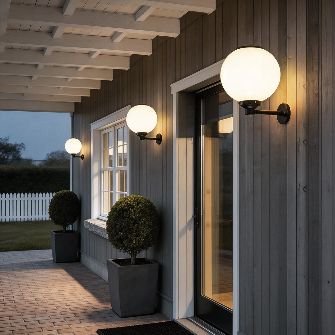 White outdoor globe wall sconce enhancing a contemporary outdoor seating area with elegant ambient light.