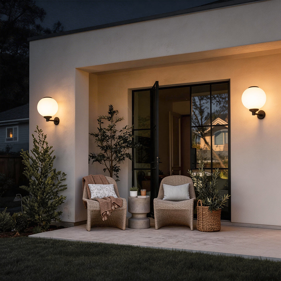 White outdoor globe wall sconce illuminating a modern patio entrance with warm directional glow.