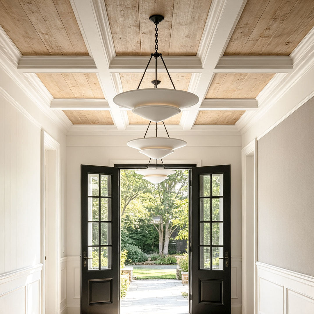 White plaster chandelier installed in an elegant hallway with coffered ceiling detail.