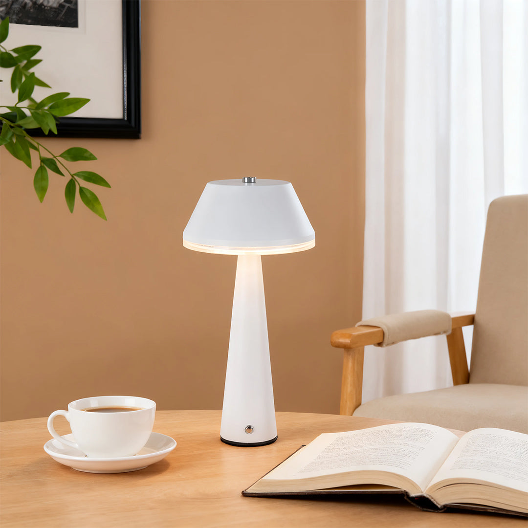 White rechargeable table lamps with a wide shade on a coffee table with an open book and cup in a sunny room. 
