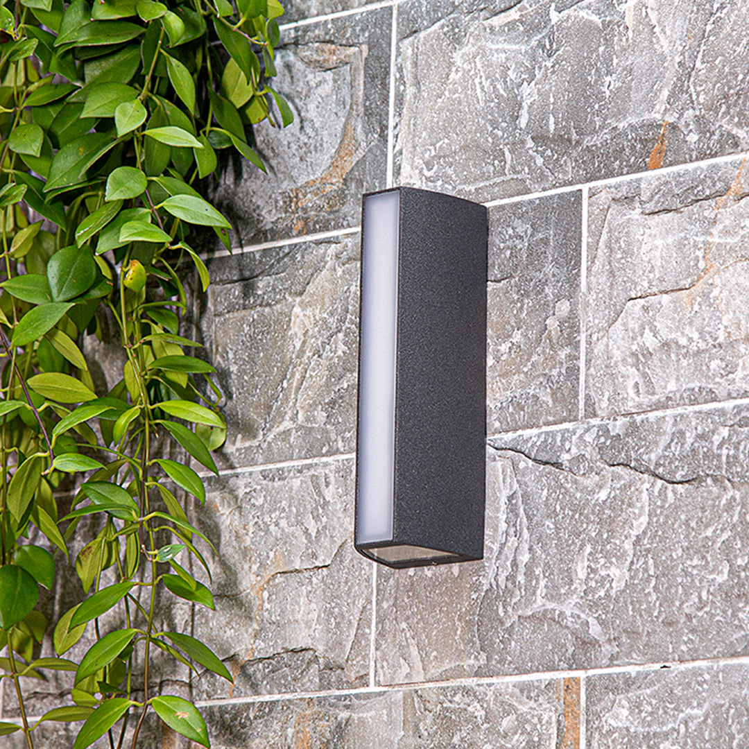 Outdoor wall light casting warm golden glow on brick surface with dramatic shadow effects