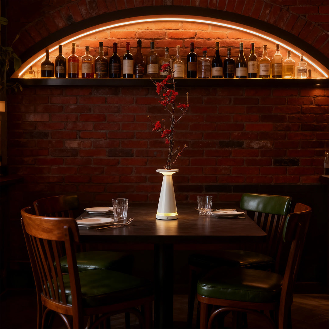 White and red vase table lamp used as a decorative centerpiece in a dimly lit, rustic restaurant setting.