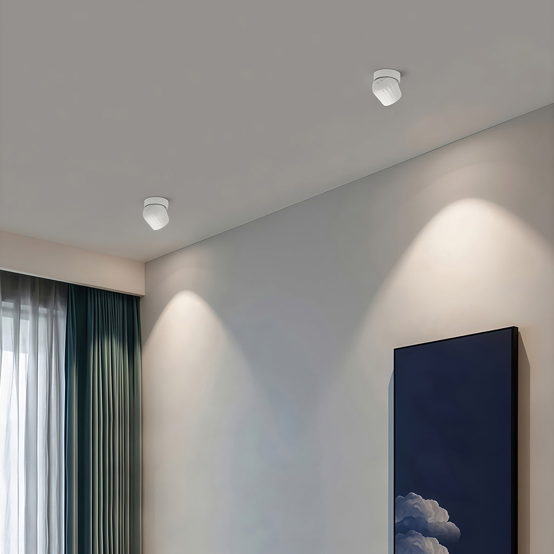 White rotating spotlights providing ambient lighting in serene bedroom with blue curtains and TV wall