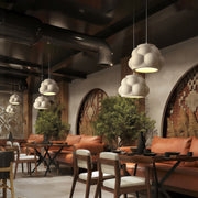 Cluster of white Single Pendant Light Fixtures hanging above tables in a cozy restaurant interior.