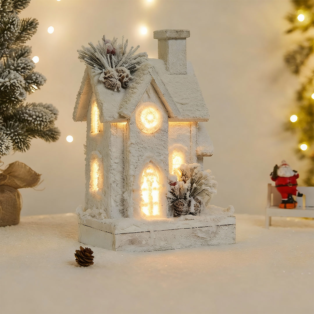 White snow-covered cottage decor, a beautiful example of light up wooden christmas houses with pine cones.
