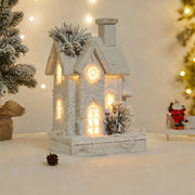 White snow-covered cottage decor, a beautiful example of light up wooden christmas houses with pine cones.
