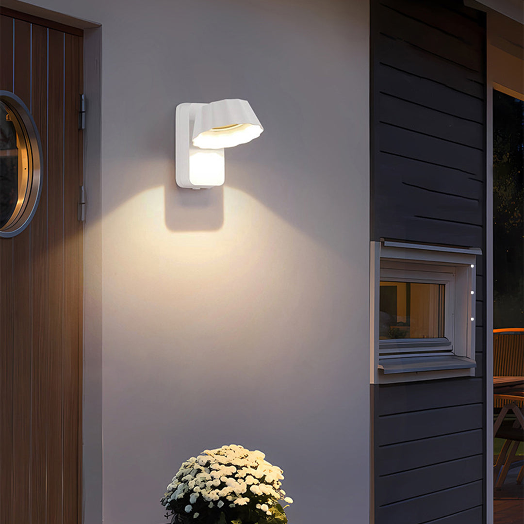 White wall-mounted light fixture on contemporary building exterior with decorative plants