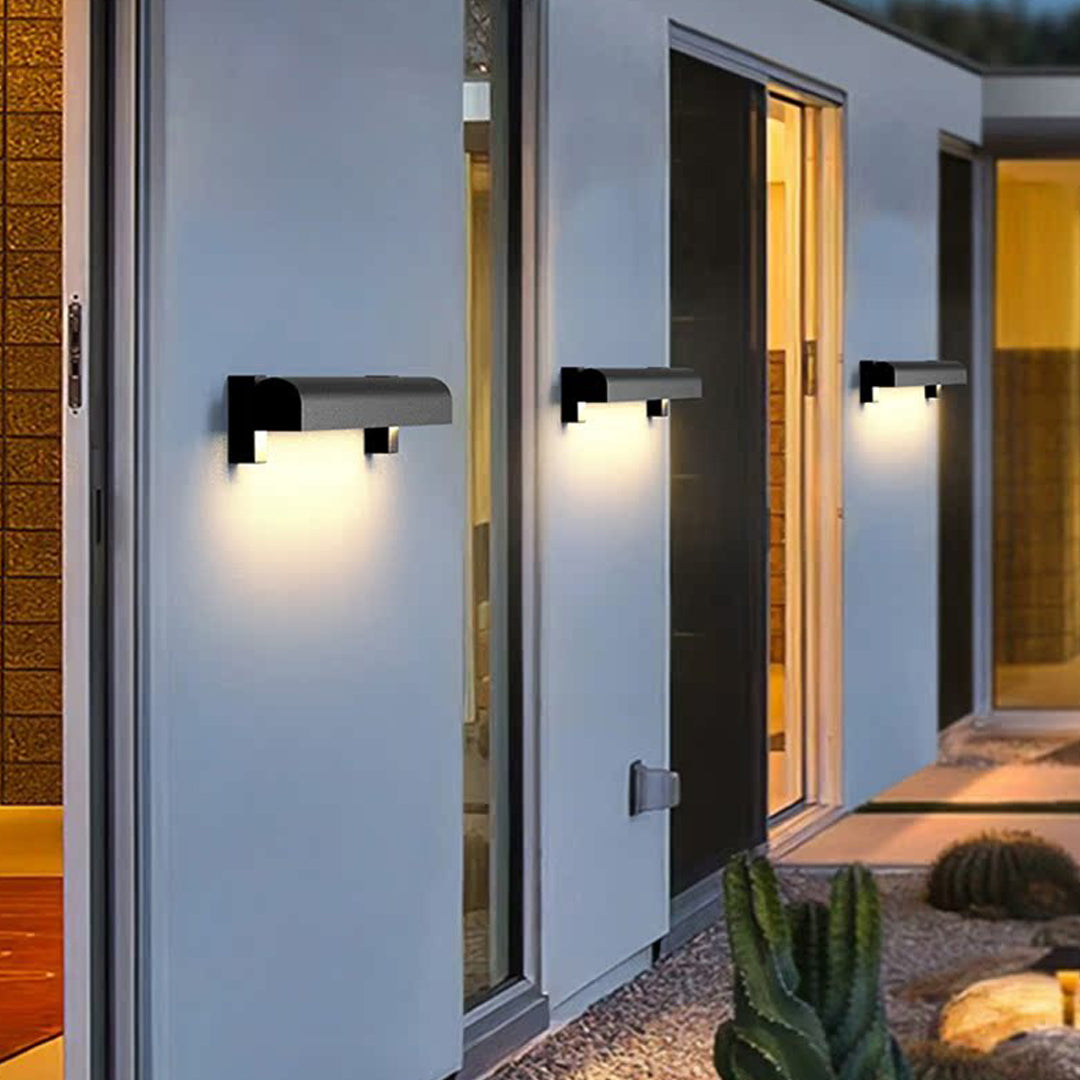 Contemporary outdoor wall sconce light fixtures illuminating a clean white exterior wall near a doorway.
