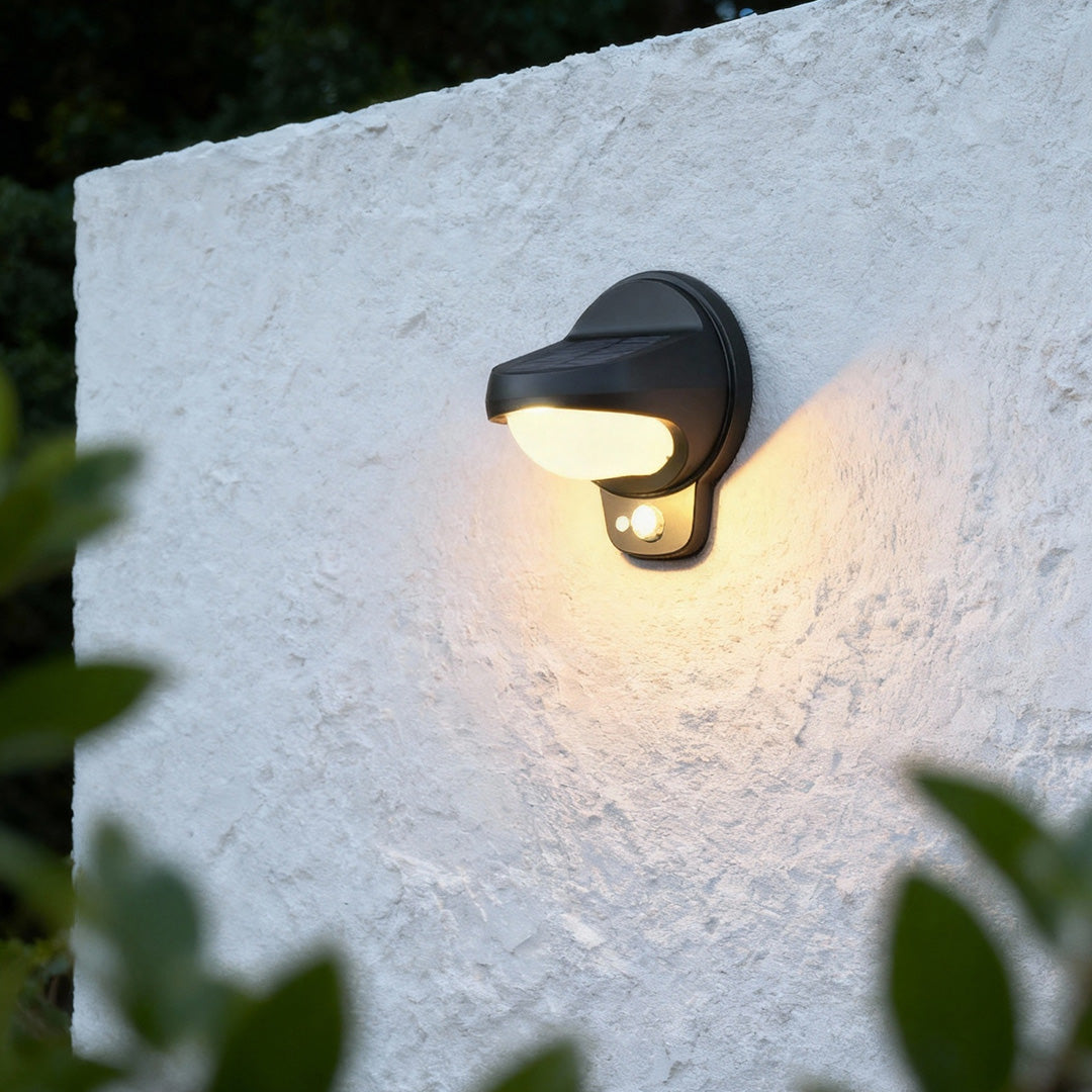 Vintage outdoor wall lights on a white outdoor wall surrounded by plants.