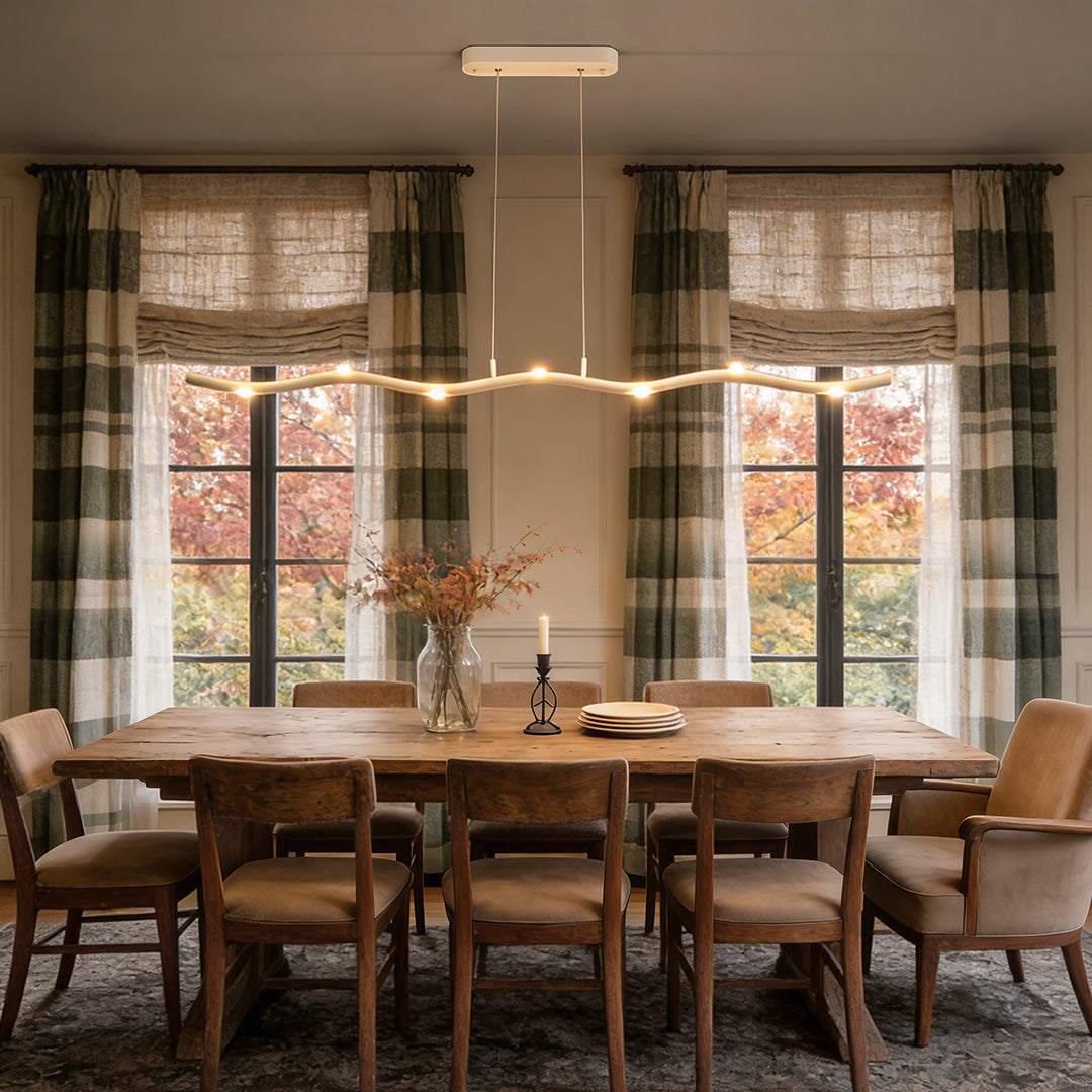White wave pendant light with a sleek design, installed above a dining table.