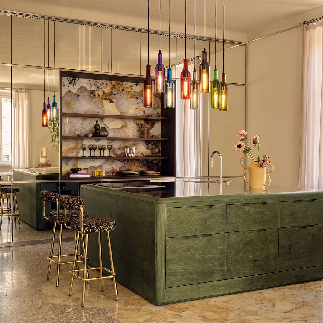 Colorful wine bottle pendant lights hanging above a green kitchen island in a modern open dining space.