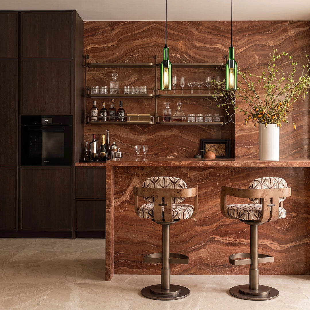 Green wine bottle pendant lights suspended above a marble bar counter in a modern home bar area.
