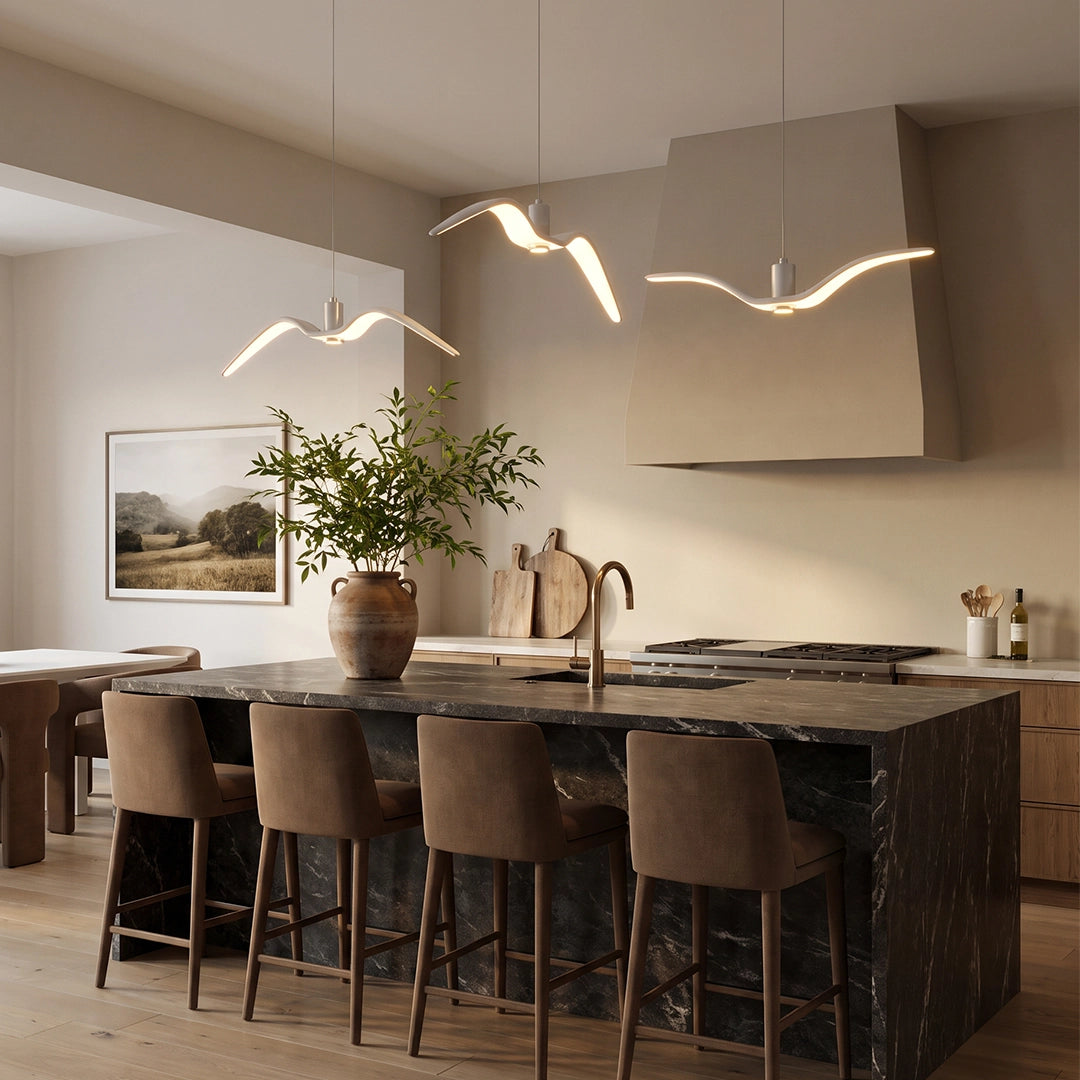 Wing pendant lights suspended above a kitchen island in a modern dining space with soft ambient lighting.