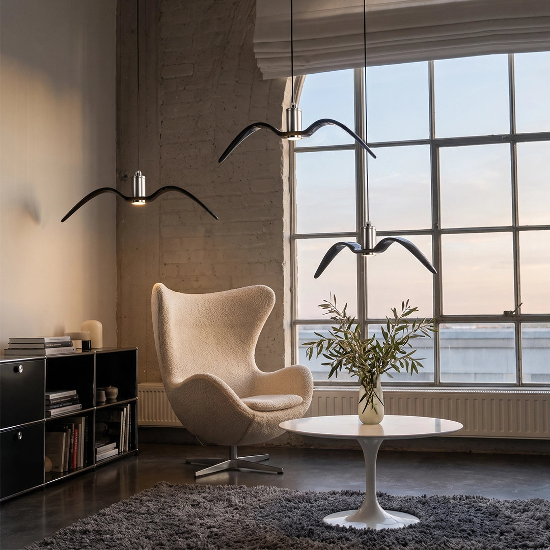 Wing pendant light hanging in a modern living room, paired with matching wall sconces and a large window.