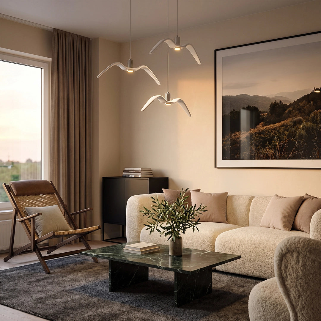 Wing pendant lights hanging above a sofa in a bright living room with framed art and warm neutral tones.