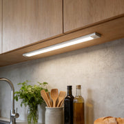 Wireless under cabinet lighting under wood kitchen cabinets shining on a clean bright counter.