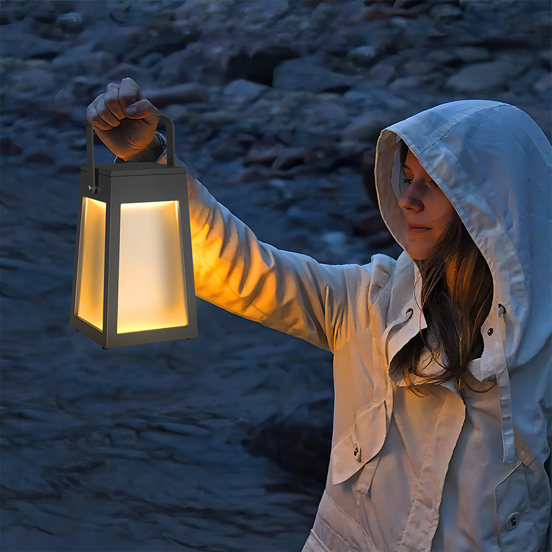 Woman holding a square camping lantern near a river at night, demonstrating its portability and bright diffused light.