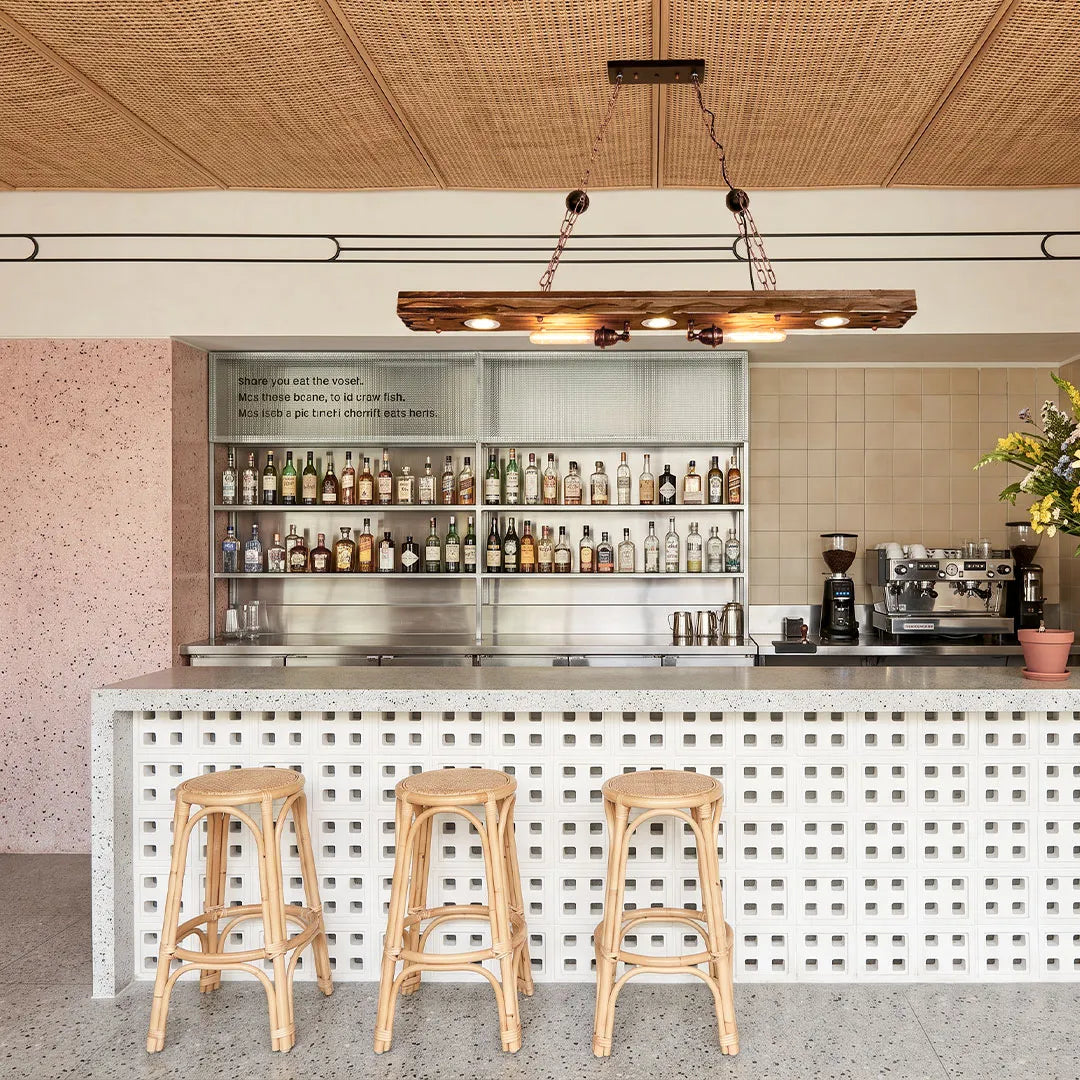 Wood and metal chandelier illuminating a bright bar area with warm linear lighting and chain details.