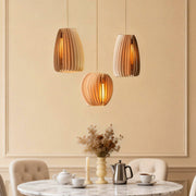 Wood slat pendant light illuminating a modern dining table with warm, natural glow.