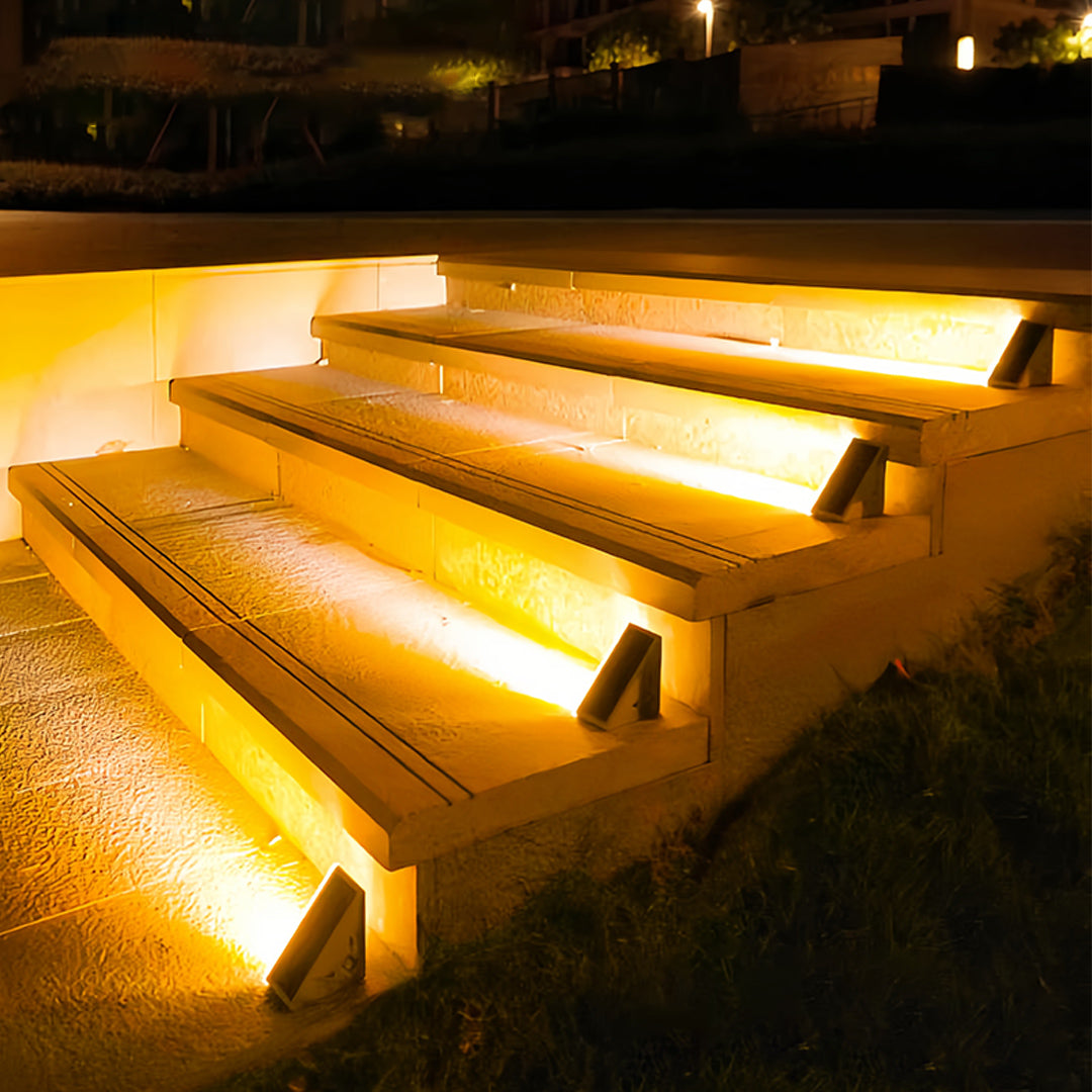 Warm LED outdoor solar step lights installed on wooden deck stairs providing safe nighttime navigation