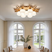 Modern wooden flush mount globe ceiling lamp with multiple frosted glass globes in a bright dining room interior.