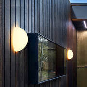 Modern outdoor lighting wall mounted lamp illuminating a vertical wooden façade.