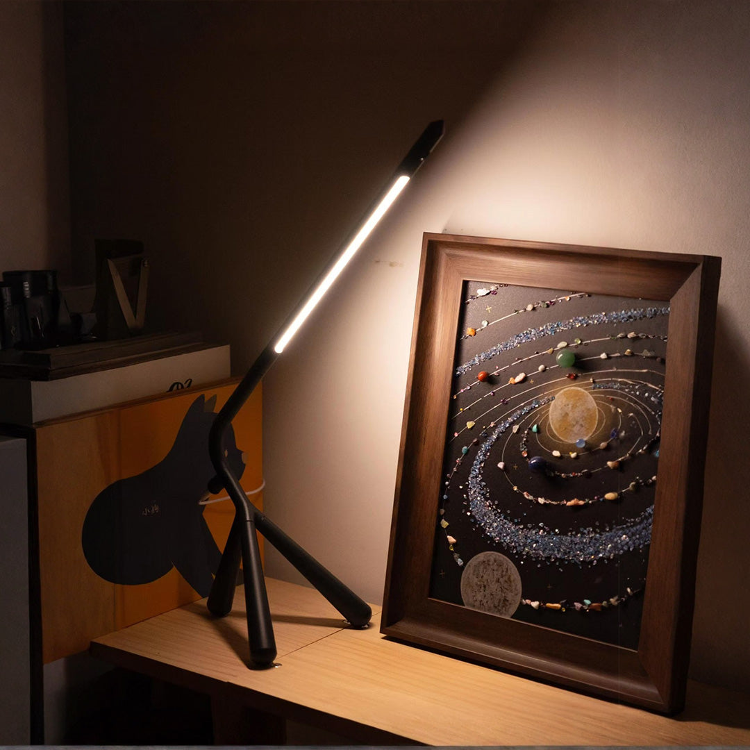 Workspace three legged table lamp with focused beam illuminating artwork and creative projects