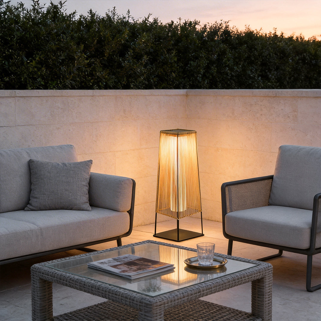 Woven outdoor floor lamp with warm light beside patio seating