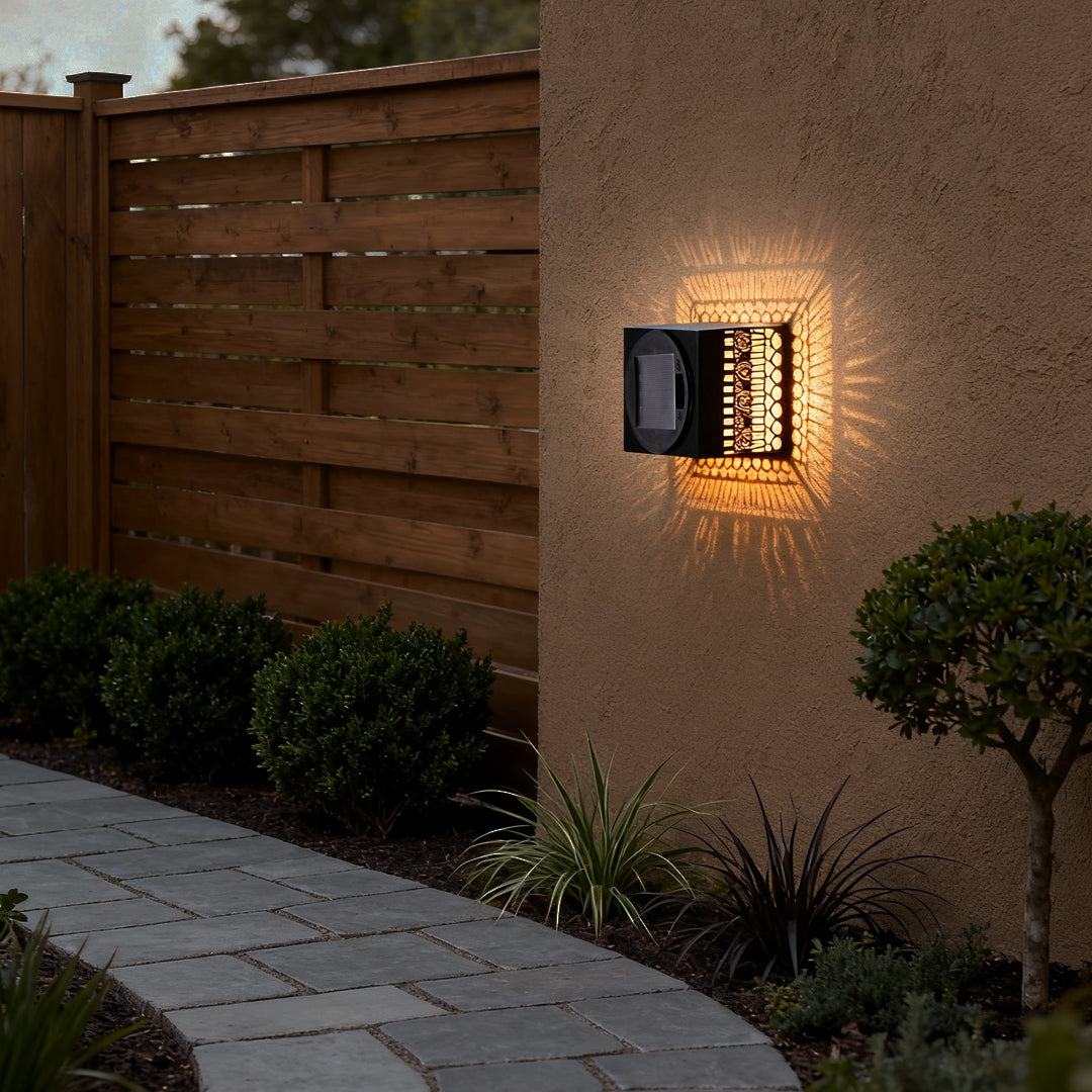 Exterior home entry illuminated by warm wrought iron outdoor wall lights mounted on the wall with intricate cutout patterns.