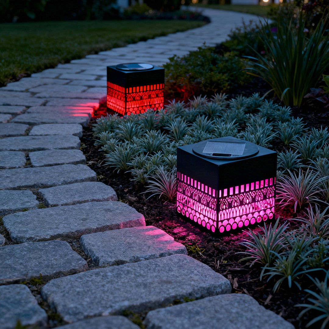 Garden walkway illuminated by multi-color ground LEDs highlighting a wrought iron outdoor wall lights decorative cube.
