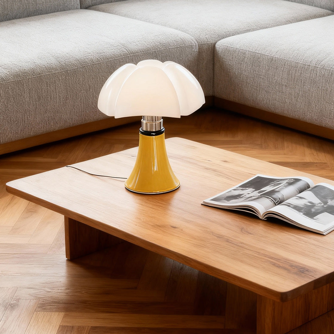 Yellow Bauhaus table lamp on wooden coffee table with magazines.